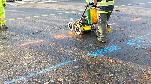 Two workers marking the road with a paint marker during structural and pavement investigations in the UK.