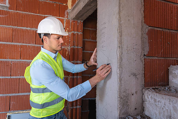A man with a shovel poses in front of a building associated with concrete testing services.