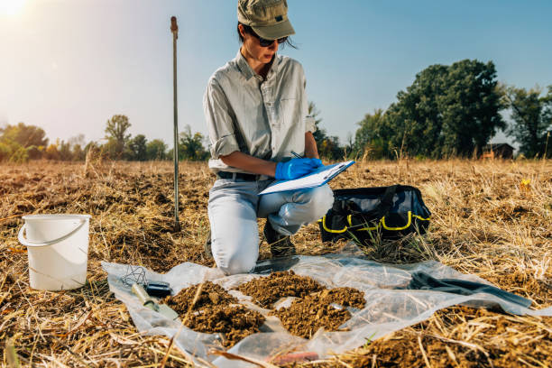 A man writes on a clipboard while examining soil, illustrating a geotechnical soil investigation process.