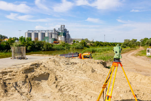 A man holding a shovel stands before a building, illustrating the concept of material testing for earthworks.