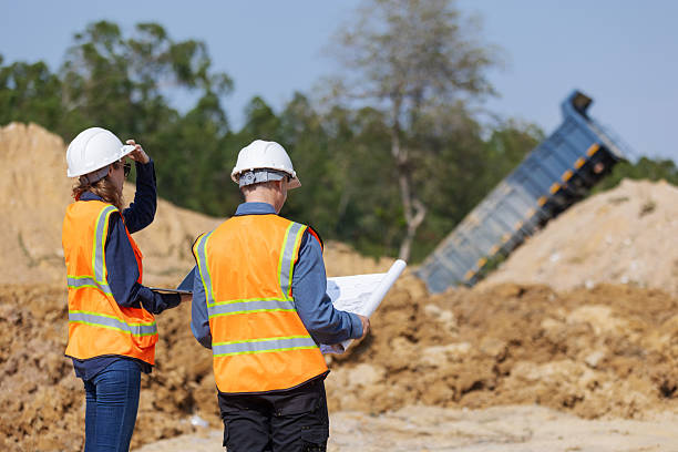 A man with a shovel stands in front of a building, representing material testing for earthworks.